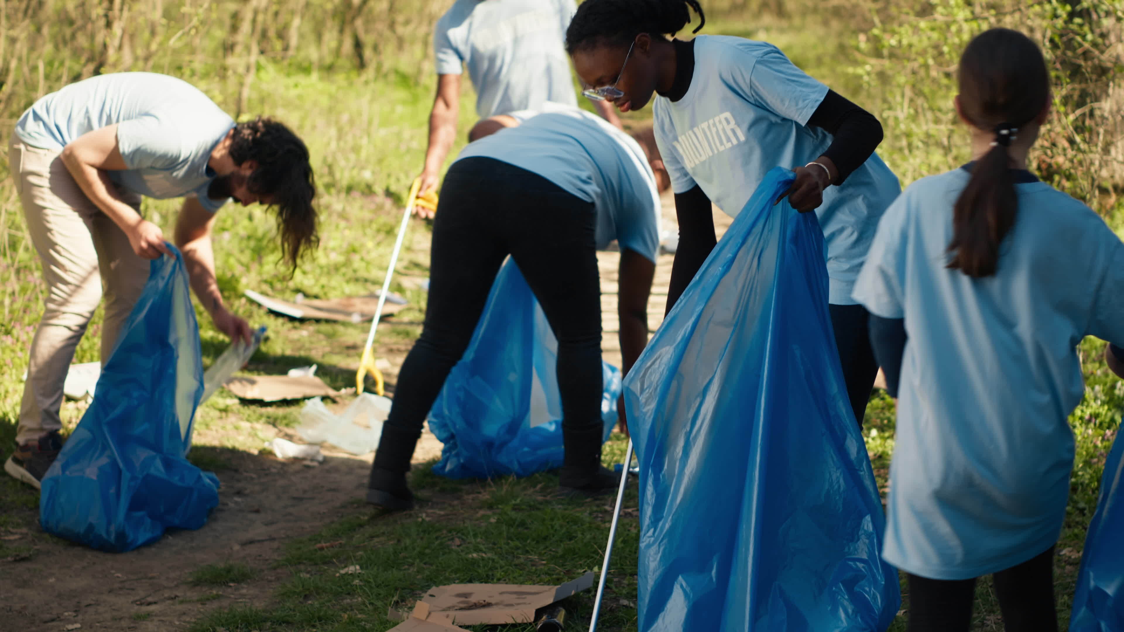 African american girl picking up trash with a long claw and garbage