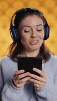 Vertical Voice actor smiling while reading ebook, portraying proud and sassy character, studio background. Woman reenacting digital novel, interpreting cheerful protagonist, reading text from tablet, camera B video