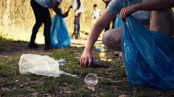 Menschen mit richtig Werkzeuge zu sauber das Wald und recyceln Plastik Abfall, Kampf Verschmutzung und illegal Schluss machen. Aktivisten Freiwilligenarbeit zu sammeln Müll von das Wald. schließen hoch. Kamera b. video