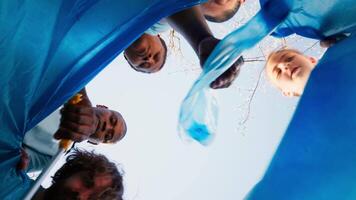 POV of environmental activists clearing the woods sorting recyclables in a disposal, collecting waste an plastic trash in a garbage bag. Individuals support ecological movement. Camera A. video