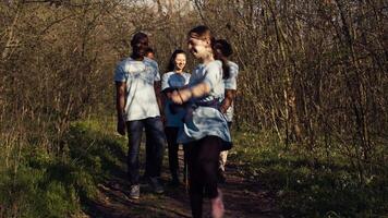 alegre orgulloso grupo de activistas refinamiento camada limpiar en un bosque, celebrando su logro en restaurar natural ambiente. personas sonriente y disfrutando su reciclaje éxito. cámara b. video