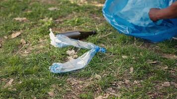 People supporting cleanup of the natural environment by grabbing recyclables and trash objects from the woods, collecting in a garbage bag. Using utensils to pick up rubbish. Close up. Camera A. video