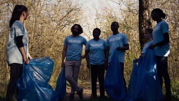voluntários grupo preparando para coletar lixo e lixo a partir de a bosques, reciclando plástico desperdício e de outros Lixo dentro bolsas. de Meio Ambiente ativistas protegendo a natureza de colheita acima lixo. Câmera b. video