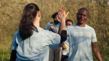 Activists congratulating each other with a high five after a successful teamwork, showing perseverance in collecting rubbish and plastic waste from forest environment. A job well done. Camera A. video