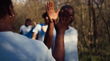 équipe chef partage une haute cinq avec sa bénévoles membres après litière nettoyer succès, louant chaque autre et sentiment satisfait avec la nature préservation. collecte ordures et nettoyage. caméra b. video