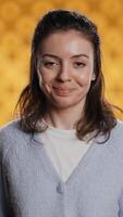 Vertical Cheerful woman happily doing salutation hand gesture, feeling optimistic. Portrait of joyous caucasian person raising arm to greet someone, gesturing, isolated over studio background, camera B video