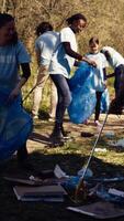 Group of diverse volunteers collecting rubbish from the woods and recycling in a garbage disposal bag, litter cleanup responsibility. Ecology activists picking up trash and plastic waste. Camera B. video