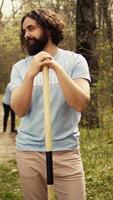 Portrait of two activists clearing up the forest surroundings by collecting garbage, growing new trees and picking up trash. Eco friendly enthusiasts preserving environments and wildlife. Camera B. video