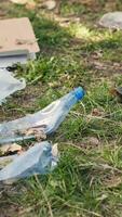 volontär- använder sig av tång verktyg till samla skräp och plast avfall från de skog, lagring skräp i en sopor väska och rena de naturlig miljö. aktivist gripa tag i skräp. stänga upp. kamera a. video