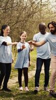 allegro orgoglioso squadra di attivisti aderire forze per pulito un' foresta, festeggiare loro il volontariato opera di collegamento mani insieme. contento persone mostrando responsabilità per il ambiente. telecamera b. video