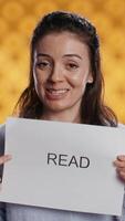 Vertical Woman holding message in hands urging people to read more, talking about importance of lecture, isolated over studio background. Bookworm promoting literacy concept, camera B video