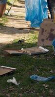 diverso hombres voluntarios recoger arriba basura y el plastico basura con tenazas, trabajando a combate ilegal dumping y preservar natural bosque ambiente. activistas trabajar como voluntario para camada limpiar. cámara una. video