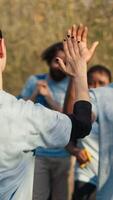 Activists congratulating each other with a high five after a successful teamwork, showing perseverance in collecting rubbish and plastic waste from forest environment. A job well done. Camera A. video