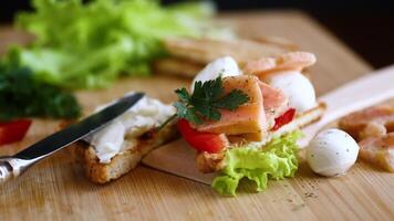 gebraten Toast mit Lachs, Sahne Käse, Salat, auf ein hölzern Tabelle video