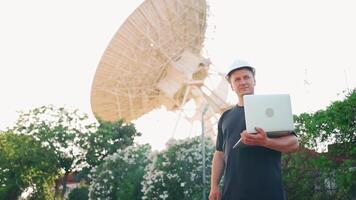 un hombre en un difícil sombrero participación ordenador portátil al aire libre video