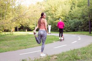 ajuste mujer calentamiento arriba piernas antes de corriendo ejercicios en pie corriendo pista en verano parque foto