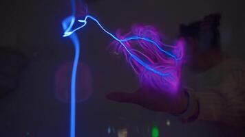 Hand touching plasma ball with blue violet electric lightning in lab video