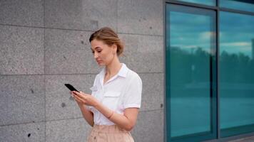 souriant femme d'affaires en utilisant téléphone intelligent tandis que en marchant près bâtiment video