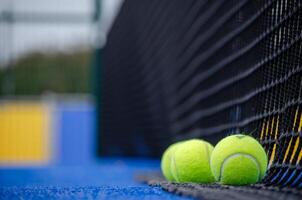 selective focus, balls next to a paddle tennis court net, racket sports concept photo