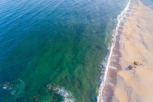top aerial view of the shore of an empty beach in summer at sunrise, drone shot photo