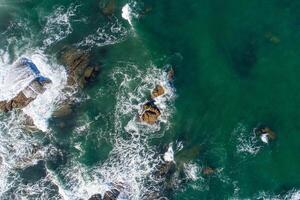 Aerial overhead drone view of waves on the rocks of the shore photo