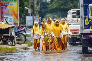 A group of junior high school students returning home from school crossed flood waters in Gresik Regency, Indonesia, 21 February 2024. photo