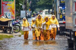 A group of junior high school students returning home from school crossed flood waters in Gresik Regency, Indonesia, 21 February 2024. photo