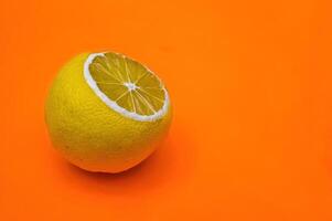 A yellow lemon isolated on a plain orange background looks fresh photo