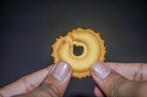 mano participación un galleta en un oscuro antecedentes foto