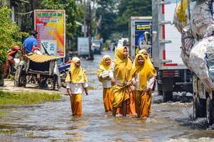 A group of junior high school students returning home from school crossed flood waters in Gresik Regency, Indonesia, 21 February 2024. photo