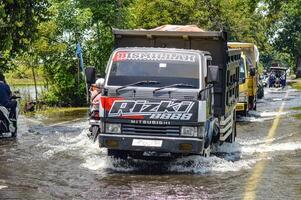 varios vehículos tal como camiones, bicicletas y carros fueron atrapado por agua de inundación en griego regencia, Indonesia, 21 febrero 2024. foto