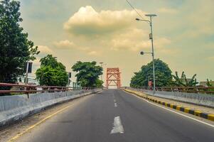 a lonely concrete arch bridge with no vehicles photographed from the middle of the highway photo