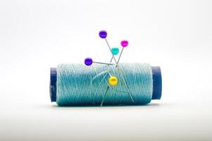a roll of sewing thread pierced by a pin isolated on white background with copy space photo