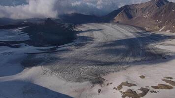 Aerial view glacier carves through mountains Earth's masterpiece Glacier in winter landscape haven for tranquility northern aesthetics. Amidst clouds glacier reveals Earth's rugged untouched beauty. video