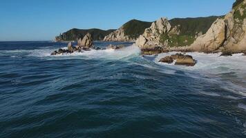 furioso mare nel il mattina a alba onde rotolo su il roccioso riva spray vola in il cielo video