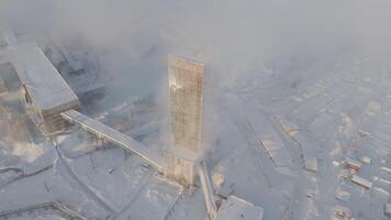 järn malm brytning antenn se av extraktion torn järn malm brytning mitt i snö kontrast av industri och natur. järn malm brytning industriell dansa i snö märkning synergi mänsklig strävan och jordens frikostighet. video