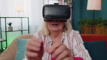 Senior woman using virtual reality VR app headset helmet to play simulation 3D 360 game online video