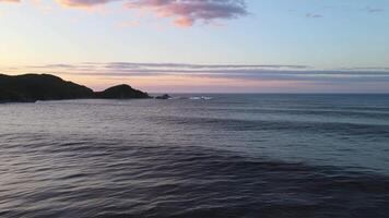 enfurecido mar dentro a manhã às alvorecer ondas lista em a rochoso costa spray sobe para dentro a céu video