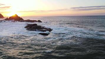 furioso mar en el Mañana a amanecer olas rodar en el rocoso apuntalar rociar se eleva dentro el cielo video