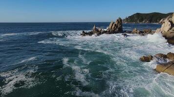 enfurecido mar dentro a manhã às alvorecer ondas lista em a rochoso costa spray sobe para dentro a céu video