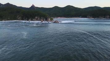 furioso mar en el Mañana a amanecer olas rodar en el rocoso apuntalar rociar se eleva dentro el cielo video