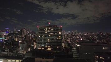 Atmospheric midnight cityscape with illuminated buildings against cloudy sky video