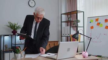 Senior business man examining graphs, analyzing, managing finance documents report at home office video