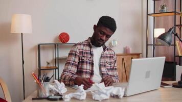 Sad young man working at home office crumples throwing heets of paper with bad ideas and mistakes video