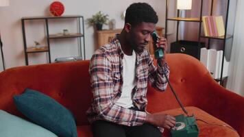 Young adult african american man enjoying talking on retro phone conversation with friends at home video