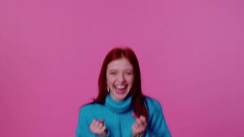 Teen girl in blue sweater shouting, raising fists in gesture I did it, celebrating success, winning video