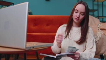 Woman doing, planning home budget on laptop and counting money, girl checking dollar cash income video