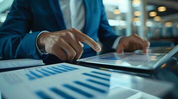 Close up businessman hand using tablet and pointing on summary report at office. Male businessman reviews a summary report on tablet. photo