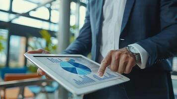 Close up businessman hand using tablet and pointing on summary report at office. Male businessman reviews a summary report on tablet. photo