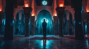 Muslim man standing praying on night in the mosque photo